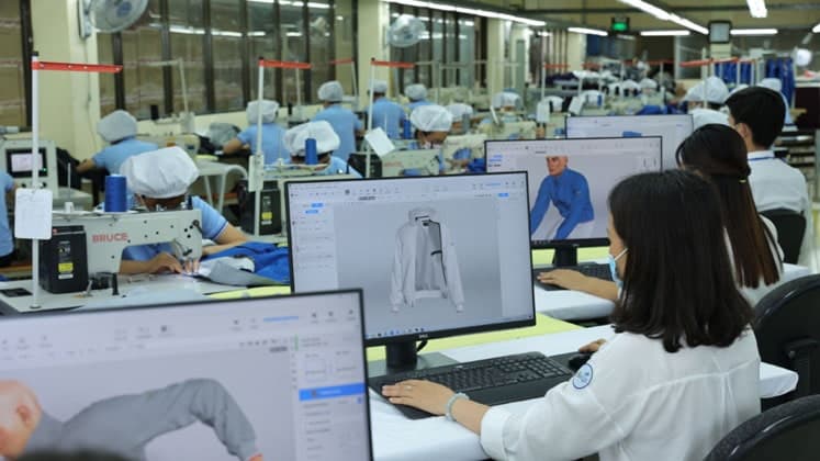Product development team reviewing a garment sample beside an active production floor
