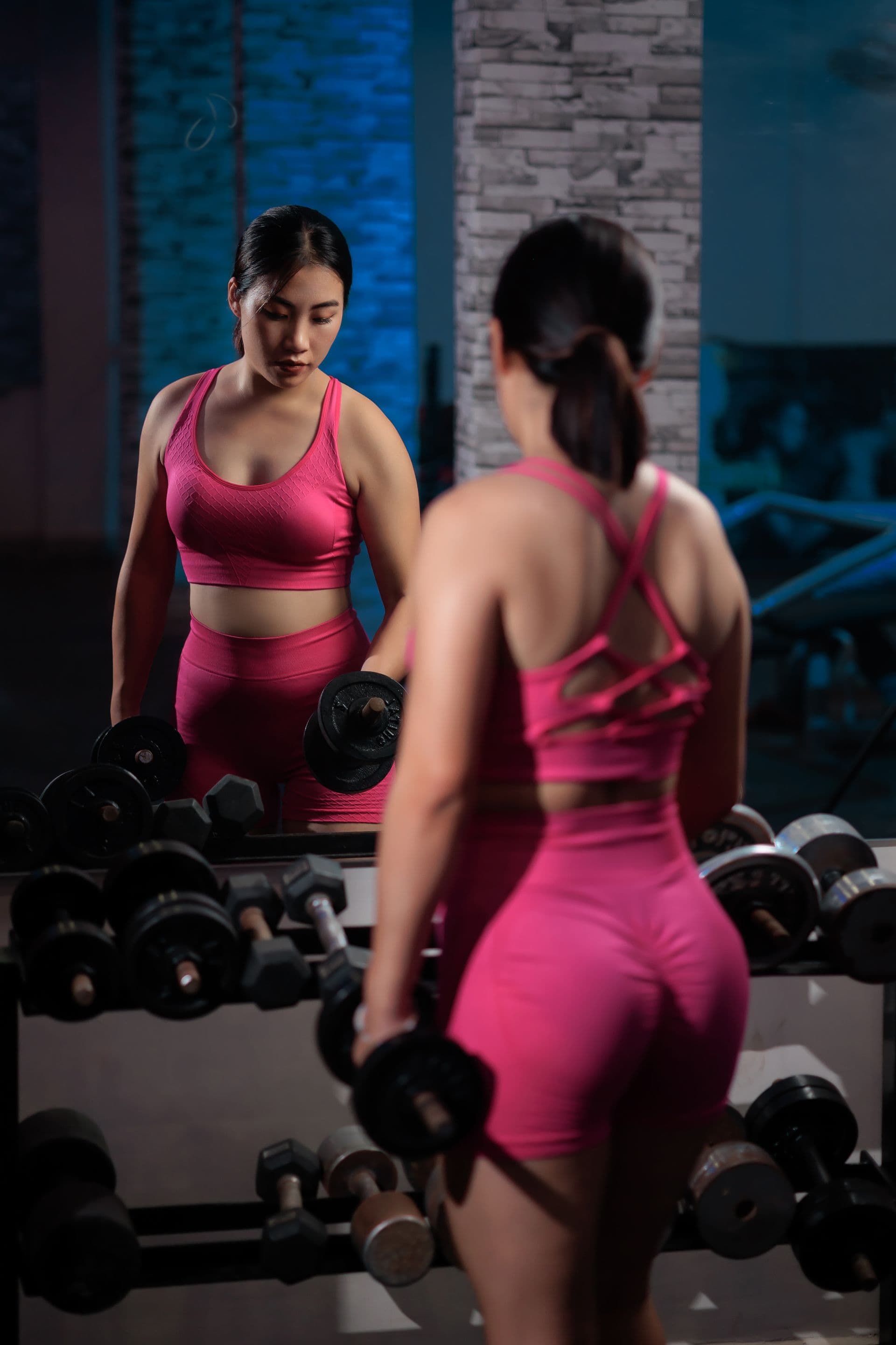 Referencia editorial proporcionada por el usuario de un conjunto sin marca de sujetador deportivo y short rosas en un gimnasio, usada para ilustrar una discusión sobre el sistema de producto de una colección de training en lugar de un registro de producto de inPACE