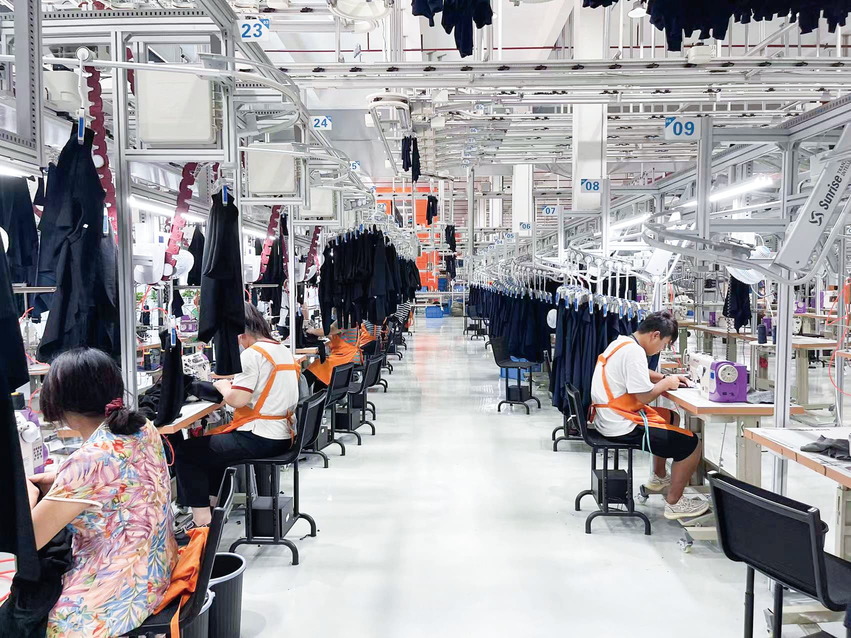 Activewear garments moving through a real factory hanging-production line for wholesale customisation