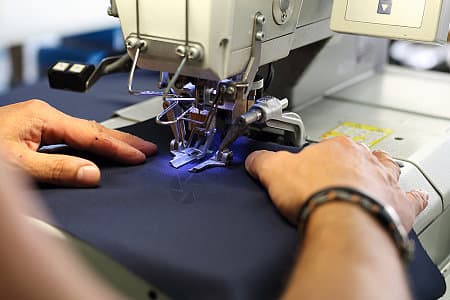 Sewing machine operator stitching dark performance fabric for a custom padel apparel sample