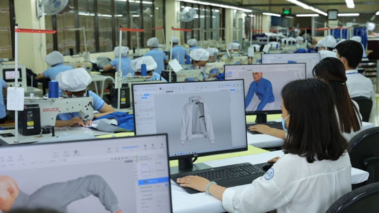 Product development team reviewing a garment sample beside an active production floor