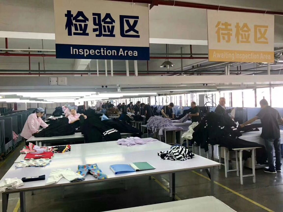 Garment inspection area with workers reviewing finished clothing before packing