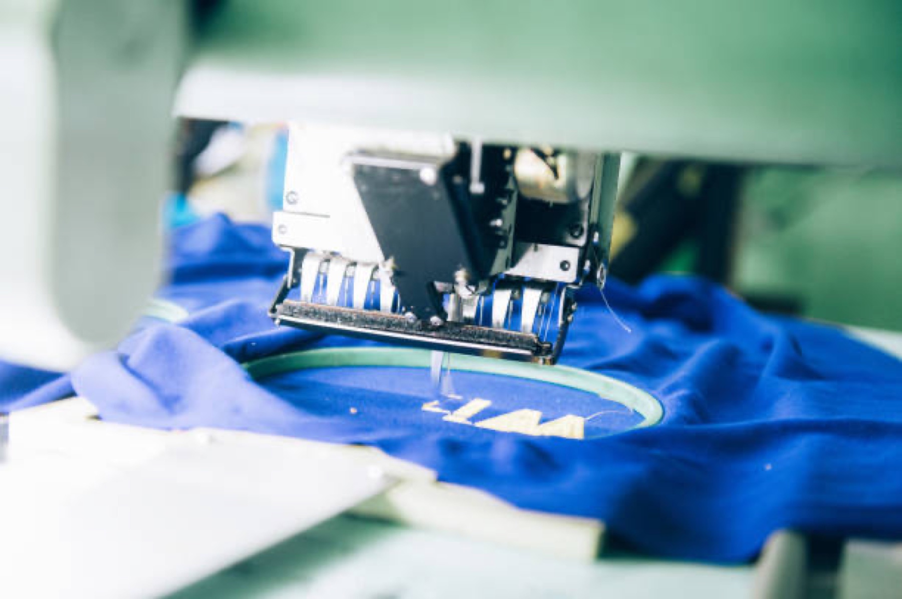 Embroidery machine applying an approved brand mark to an activewear garment during a wholesale branding project