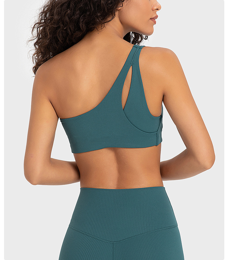 Back view of a teal one-shoulder sports bra showing the strap path and back coverage as a design reference