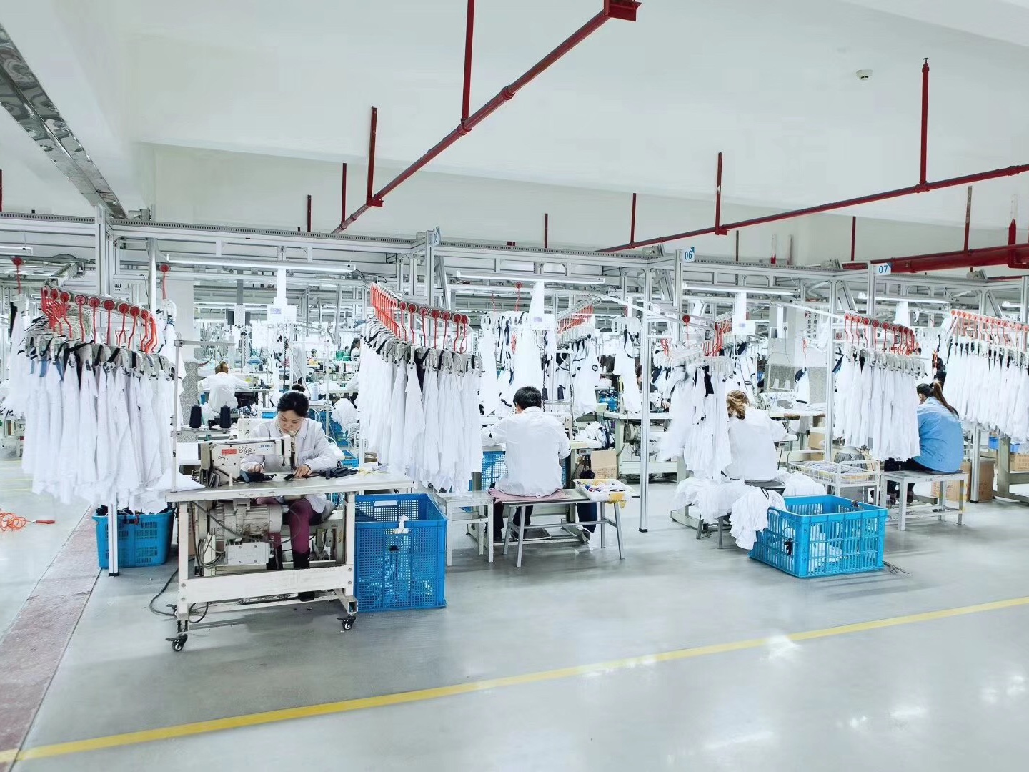 Real activewear factory sewing line with organised workstations and white garments in production